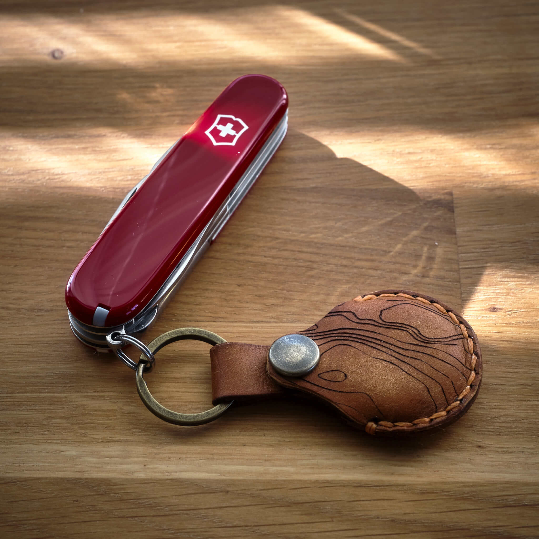 Victorinox Super Tinker med en handsydd brun Apple AirTag nyckelring i läder med topografiskt mönster som är tillverkad i Sverige.