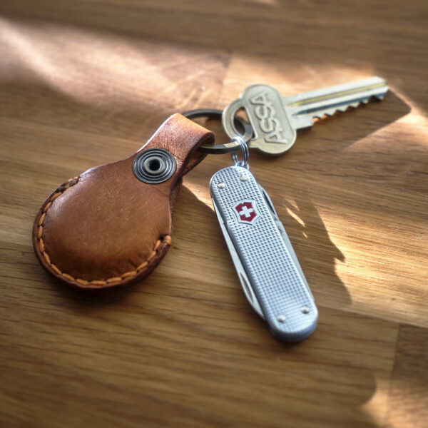 Victorinox Classic Alox med handsydd brun Apple AirTag nyckelring i läder med topografiskt mönster som är tillverkad i Sverige.