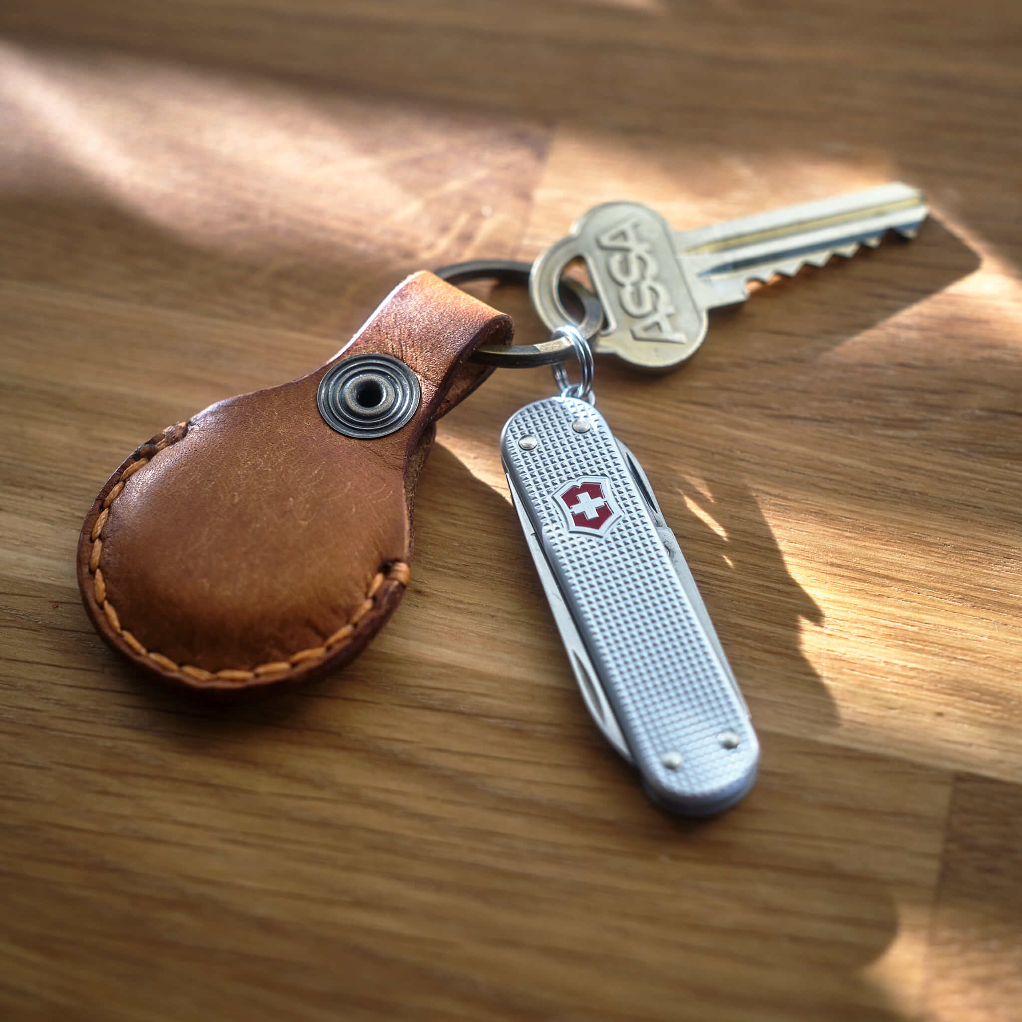 Victorinox Classic Alox med handsydd brun Apple AirTag nyckelring i läder med topografiskt mönster som är tillverkad i Sverige.