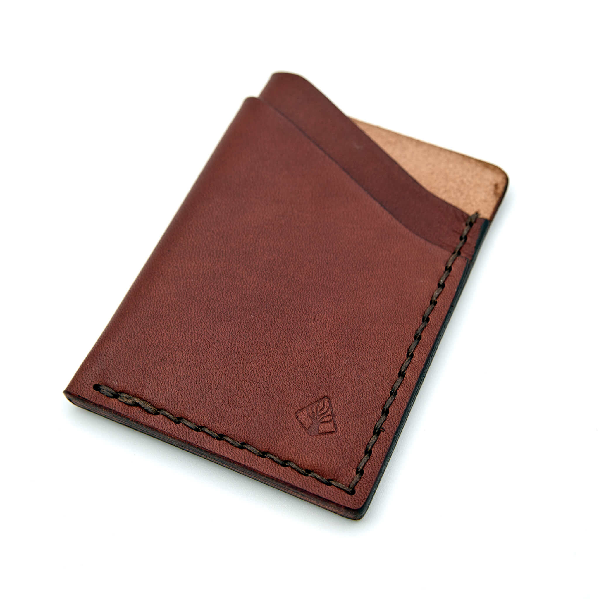 Minimalistisk handsydd plånbok Old Tjikko i vegetabiliskt garvat brunt läder och färgmatchad tråd. Tre fickor med plats för kort och sedlar. Tillverkad i Sverige.