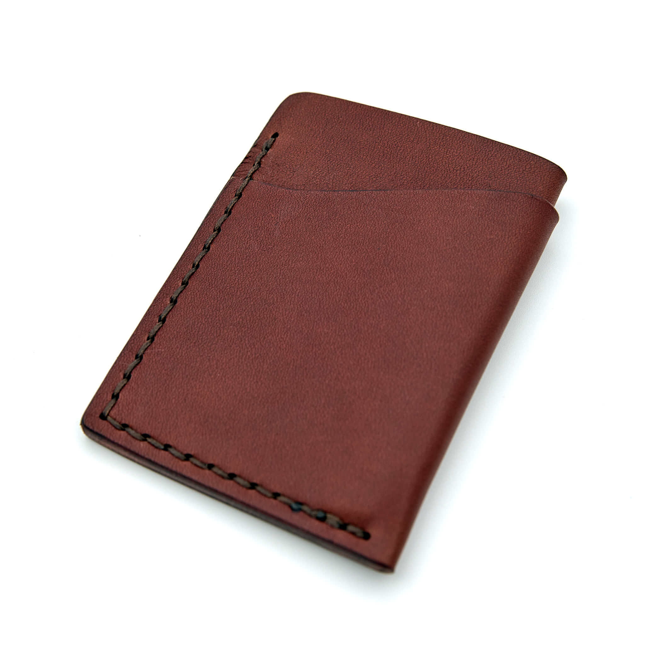 Minimalistisk handsydd plånbok Old Tjikko i vegetabiliskt garvat brunt läder och färgmatchad tråd. Tre fickor med plats för kort och sedlar. Tillverkad i Sverige.