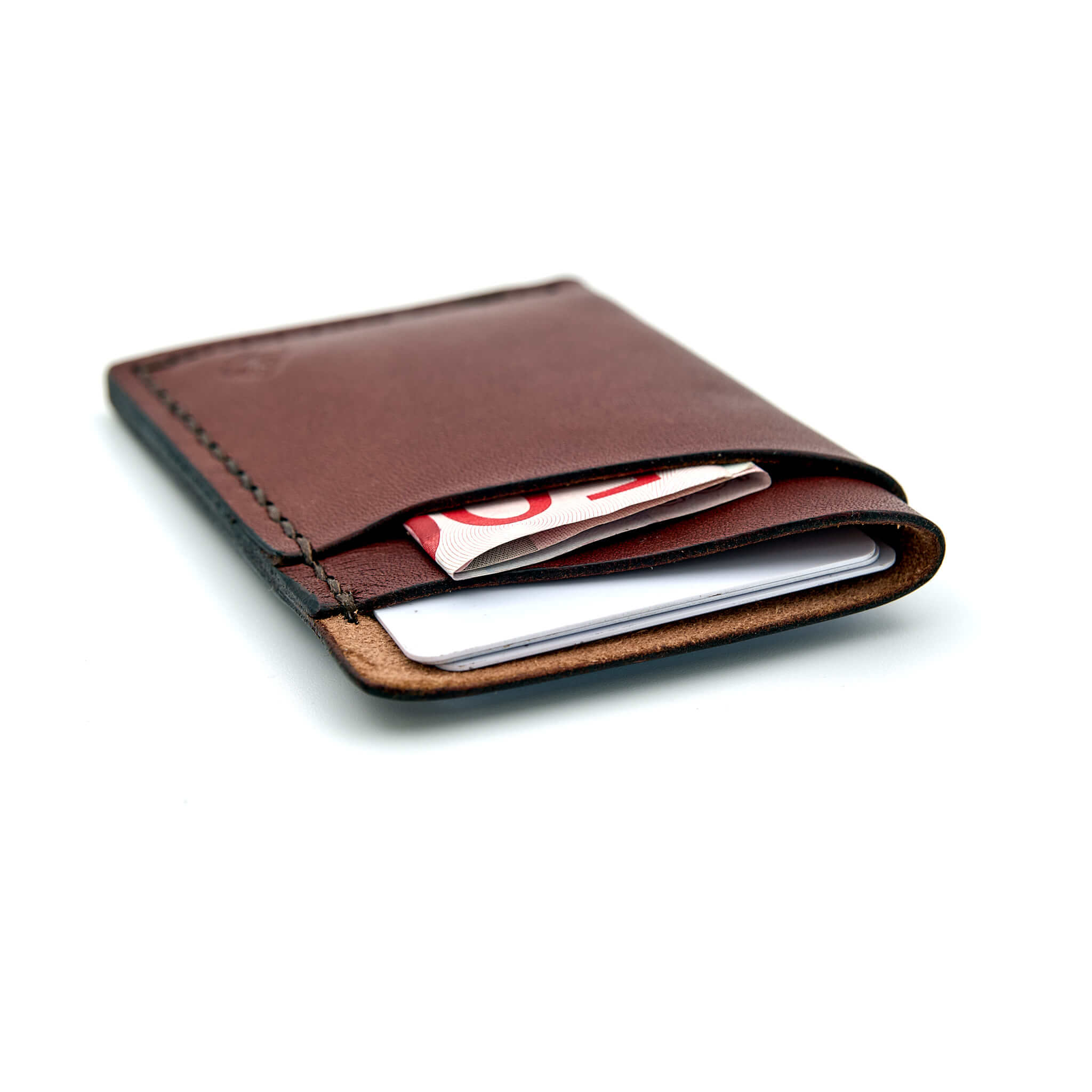 Minimalistisk handsydd plånbok Old Tjikko i vegetabiliskt garvat brunt läder och färgmatchad tråd. Tre fickor med plats för kort och sedlar. Tillverkad i Sverige.