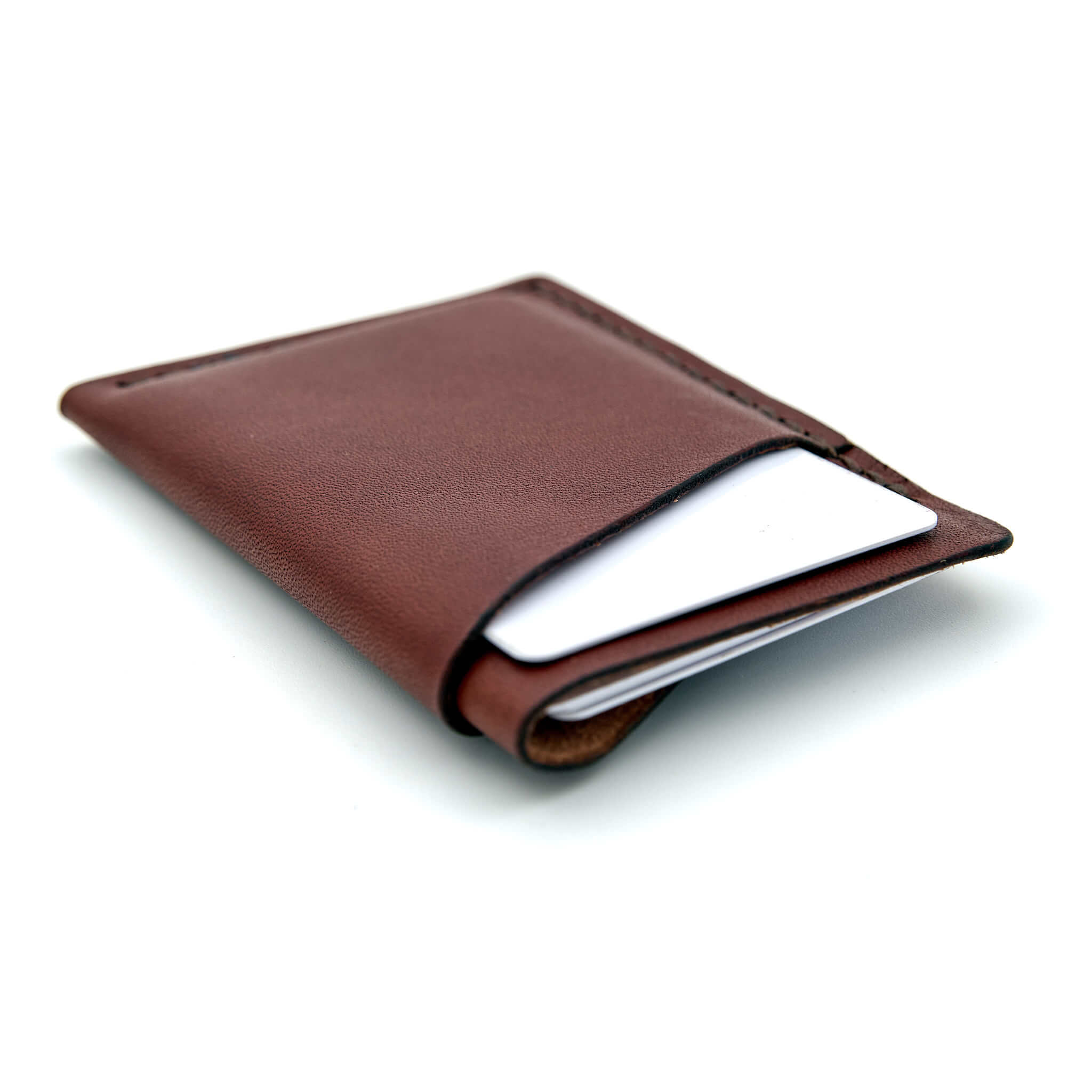 Minimalistisk handsydd plånbok Old Tjikko i vegetabiliskt garvat brunt läder och färgmatchad tråd. Tre fickor med plats för kort och sedlar. Tillverkad i Sverige.