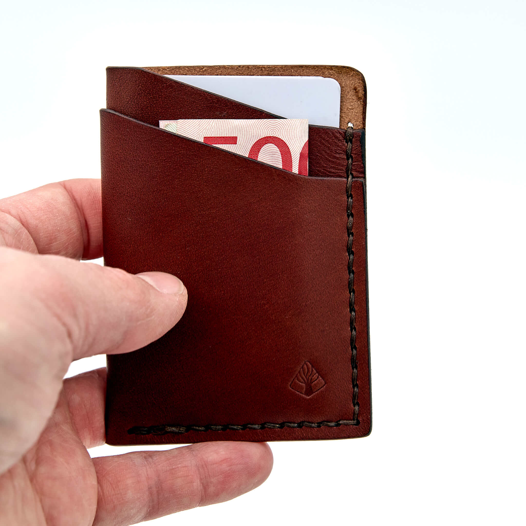 Minimalistisk handsydd plånbok Old Tjikko i vegetabiliskt garvat brunt läder och färgmatchad tråd. Tre fickor med plats för kort och sedlar. Tillverkad i Sverige.