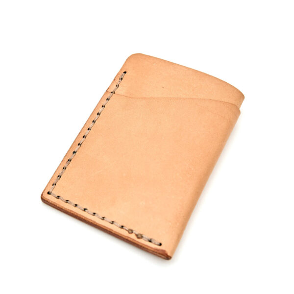 Minimalistisk handsydd plånbok Old Tjikko i vegetabiliskt garvat naturfärgat läder och färgmatchad tråd. Tre fickor med plats för kort och sedlar. Tillverkad i Sverige.
