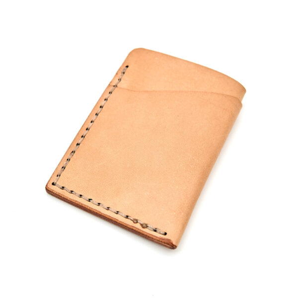 Minimalistisk handsydd plånbok Old Tjikko i vegetabiliskt garvat naturfärgat läder och färgmatchad tråd. Tre fickor med plats för kort och sedlar. Tillverkad i Sverige.