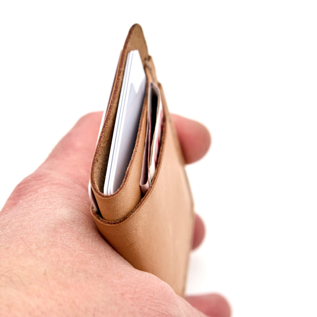 Minimalistisk handsydd plånbok Old Tjikko i vegetabiliskt garvat naturfärgat läder och färgmatchad tråd. Tre fickor med plats för kort och sedlar. Tillverkad i Sverige.