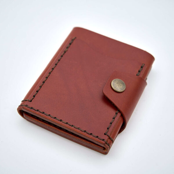 Handsydd tri-fold plånbok med knappstängning i vegetabiliskt garvat läder. Cognacfärgat läder från Tärnsjö Garveri. Tillverkad i Sverige av K Creative Craft.